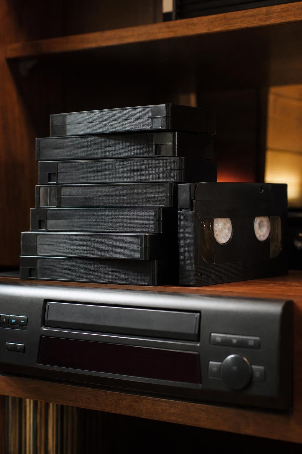 Stapel unbeschrifteter VHS-Kassetten und ein alter Videorekorder auf einem Holzregal (mit AI erstelltes Bild)